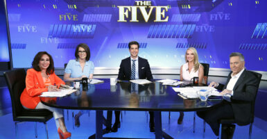 Greg Gutfeld, Dana Perino, Jesse Waters, Jessica Tarlov and Jeanine Pirro sit at the table on the set of "The Five" looking straight to the camera.