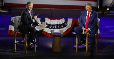 Donald Trump and Fox News host Sean Hannity sit in chairs in front of flag bunting during a 2024 town hall.