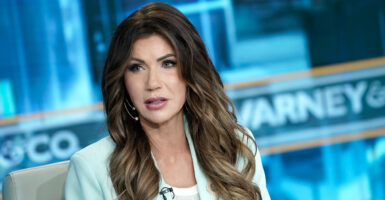 A close-up photo shows Kristi Noem wearing a light blue blazer on a Fox News set in front of a blue "Varney & Co." background.