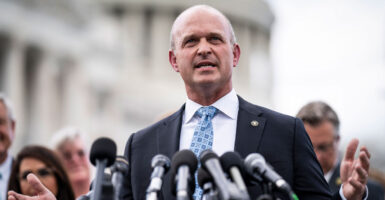 Heritage Action President Kevin Roberts speaks into a number of microphones outside the U.S. Capitol building, with a group of people behind him.