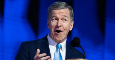Roy Cooper speaks at a lectern before a Democrat crowd.