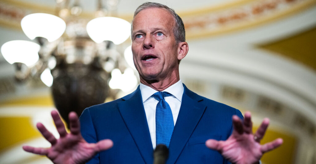 Senate Majority Leader John Thune with hands spread speaks to reporters.