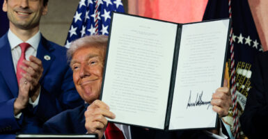 President Donald Trump holds up his executive order.