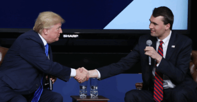 President Donald Trump, left, and Charlie Kirk, right, shake hands at a conference