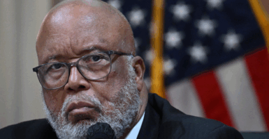 Rep Benny Thompson in a dark suit speaks into a microphone at a House committee hearing with an American flag in the background