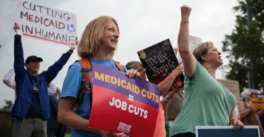 protesters hold up signs protesting cuts to Medicaid