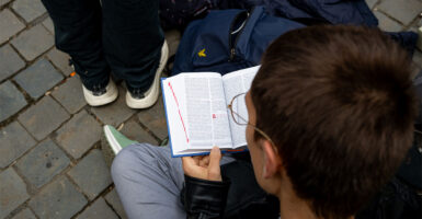 A boy sits and looks at an open bible.