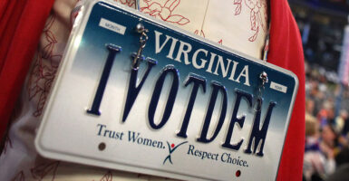 A woman wears a Virginia license plate on her back that says I VOT DEM