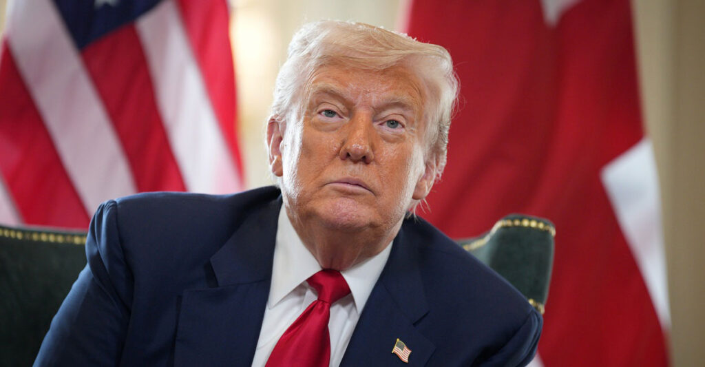 Donald Trump leans to his left as he sits in front of a microphone during a press conference.