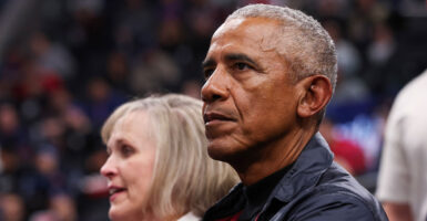 Barack Obama sits in the stands of an NBA game and looks ahead.