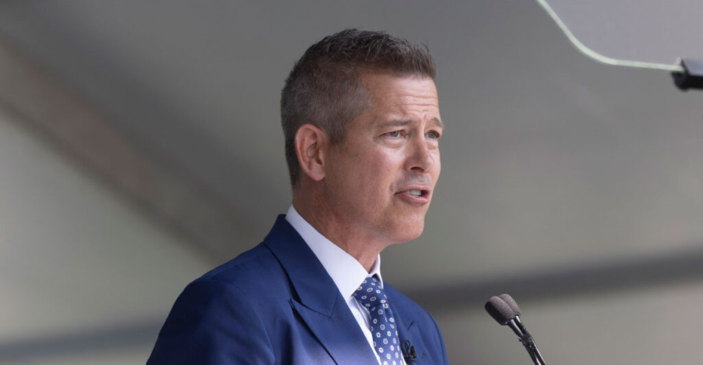 Sean Duffy looks straight ahead as he stands behind a podium and speaks into a microphone.