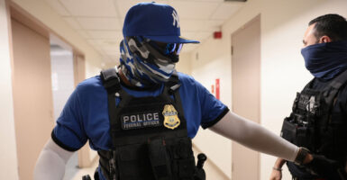 A masked ICE agent ropes off an area.