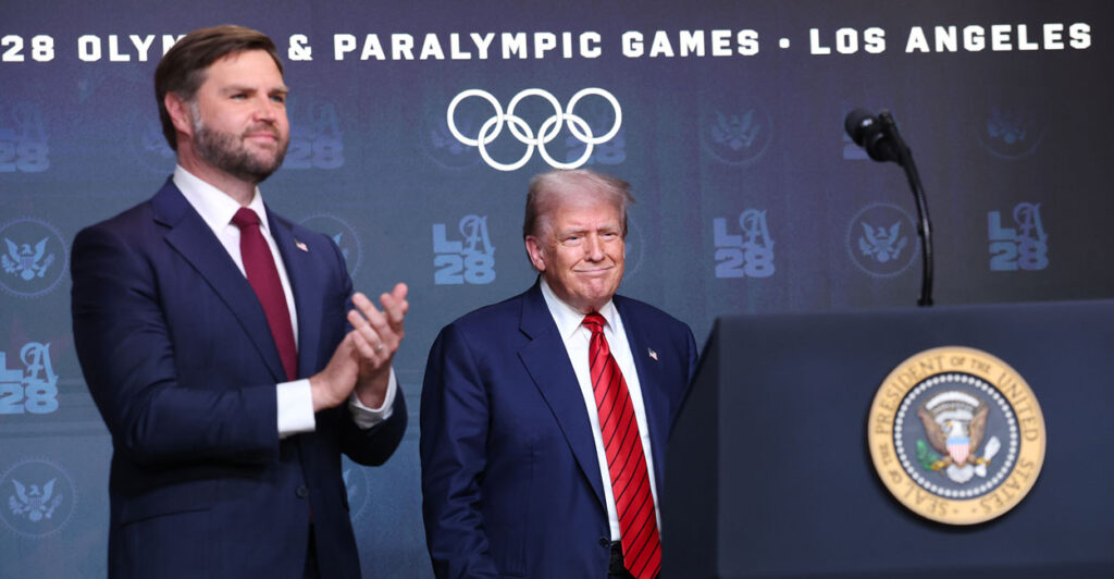 President Donald Trump and Vice President JD Vance arrive at a podium with the Olympic logo in the background.