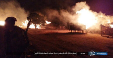 A still-shot of a nighttime attack on a village in Mozambique, depicting buildings aflame.