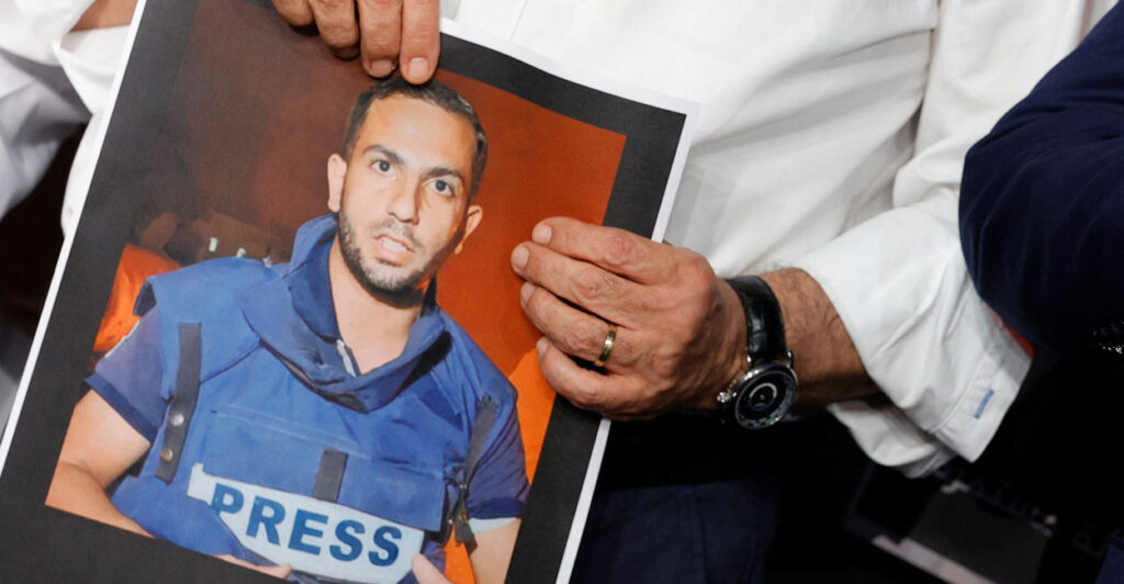An Al Jazeera anchor holds a photo of correspondent and accused Hamas terrorist Anas al-Sharif.