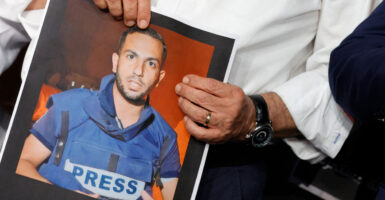 An Al Jazeera anchor holds a photo of correspondent and accused Hamas terrorist Anas al-Sharif.
