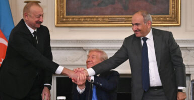 A beaming President Donald Trump (C), Azerbaijani President Ilham Aliyev (L) and Armenian Prime Minister Nikol Pashinyan shake hands after signing an agreement in the State Dining Room of the White House in Washington, DC, on August 8, 2025.