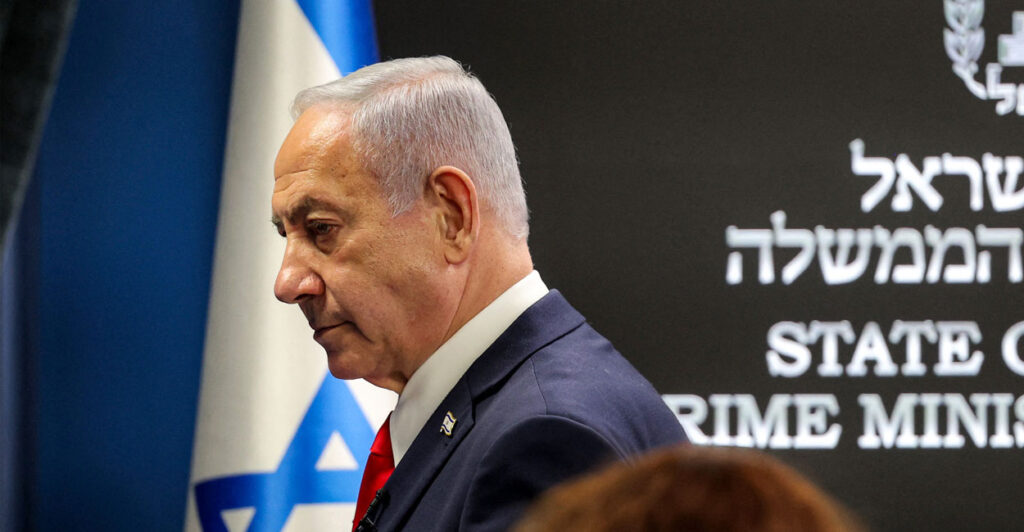Side profile of Israeli Prime Minister Benjamin Netanyahu with an Israeli flag in the background