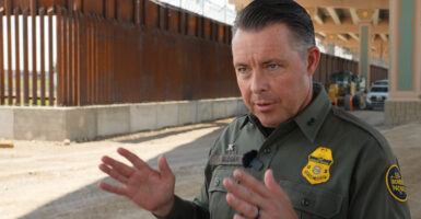 Interim Border Patrol Chief for the El Paso Sector Walter Slosar stands in his green uniform near the border wall.