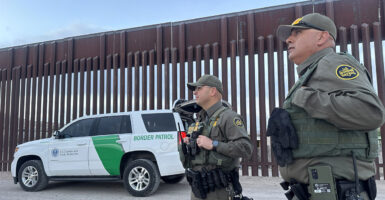 Two Border Patrol agents seen standing near the border wall in El Paso, Texas.