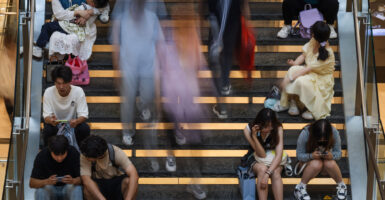 People sit on a staircase as others walk past in Chongqing, China, on May 1.