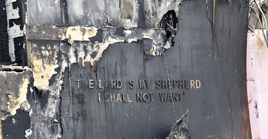A building destroyed with the words "The Lord Is My Shepherd I Shall Not Want" barely visible