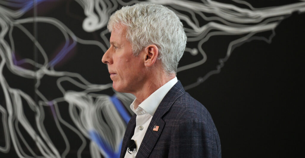 A profile shot of Energy Secretary Chris Wright, in a black jacket and open white shirt.