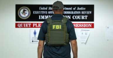 An FBI agent stands with his back turned.