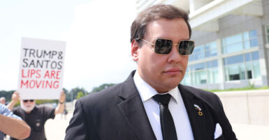 George Santos walks into court in formal attire as protestors accost him.