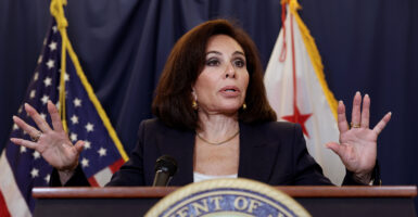 Jeanine Pirro, with her hands raised, stands behind a podium