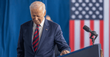 Joe Biden in a suit looks down as he walks away from a podium