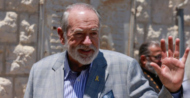 U.S. Ambassador to Israel Mike Huckabee, in a grey suit, waves while visiting the West Bank.