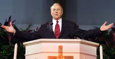 James Dobson behind the pulpit, his arms spread wide.