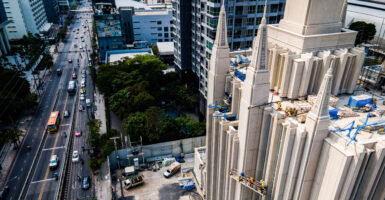 View of cars on street and construction crew while working on temple of the Church of Jesus Christ of Latter-day Saints (LDS)