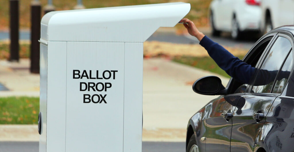A drive-up voter drops off his election ballot for the 2020 General Election in the drop box outside of the West Bloomfield Township Hall in West Bloomfield, Michigan