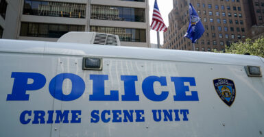Flags fly at half-staff as a New York City Police Department (NYPD) vehicle is seen outside the 345 Park Avenue building, the scene of last night's deadly shootings in Midtown Manhattan in New York on July 29, 2025.