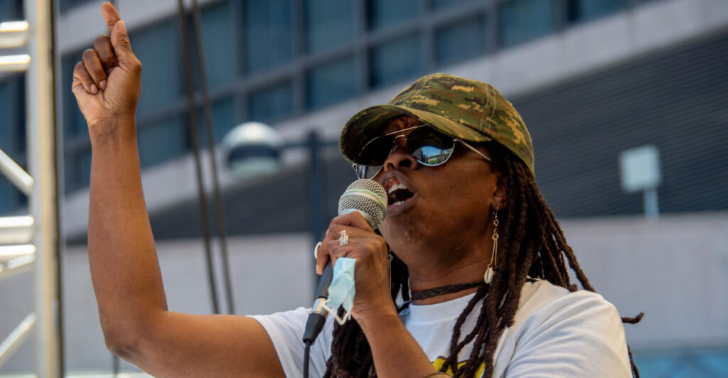 Iris Roley gestures with her finger as she holds a microphone.