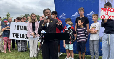 Winsome Earle-Sears in front of a sign reading "I Stand With The Loudoun 3"