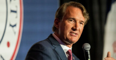 Virginia Gov. Glenn Youngkin in a dark suit on a stage speaking into a microphone