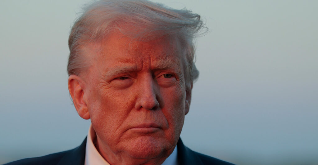 Close-up of Donald Trump against a blue late afternoon sky.
