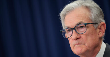 A three-quarters profile shot of Jerome Powell against a dark blue background.
