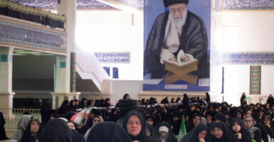 Iranian women sit beneath a portrait of Iran's Supreme Leader, Ayatollah Ali Khamenei, during a ceremony at the Imam Khomeini Grand Mosque in Tehran, Iran.
