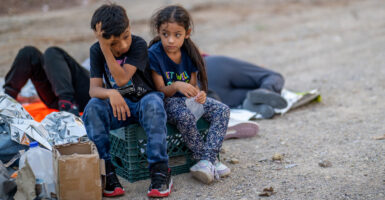 Two small illegal immigrant children sit on a crate near the border after illegally crossing into the U.S.