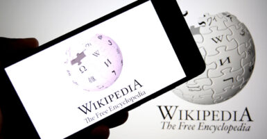 In a photo illustration, the Wikipedia logo is seen displayed on a smartphone and in the background.