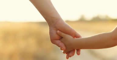 A nurturing dad holds his young daughter's hand