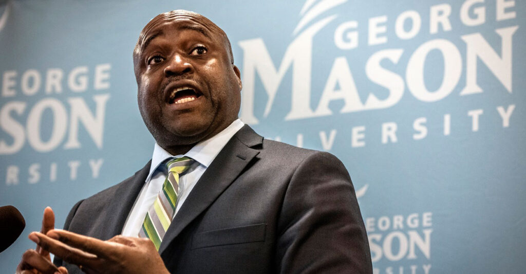 Gregory Washington stands while talking and looking to his left as he gestures with his hands.