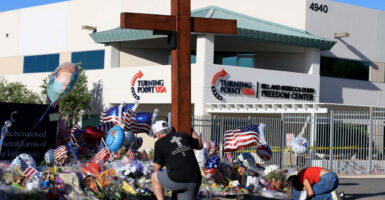 Dan Beazley and Natalia Hernandez pray at the makeshift memorial for Charlie Kirk outside of the headquarters of Turning Point USA on Tuesday in Phoenix, Arizona.