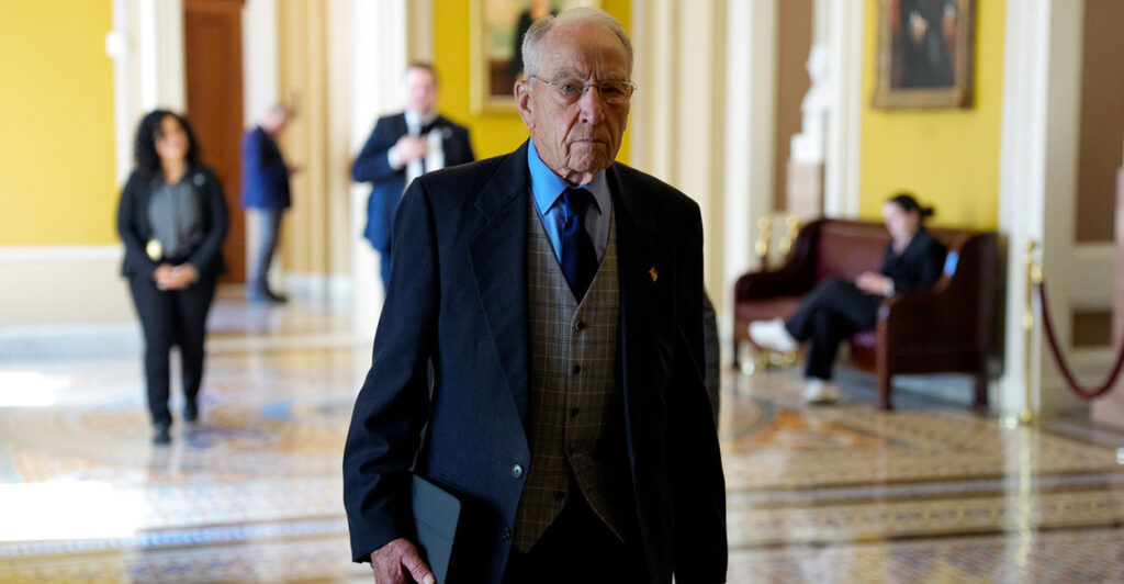 Chuck Grassley stands in a hallway with a folder in his right hand.