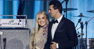 Charlie Kirk and wife Erika appear together on stage during Turning Point USA's Inauguration Eve ball on Jan. 19 in Washington with a backdrop of music instruments, amplifiers, and speakers.