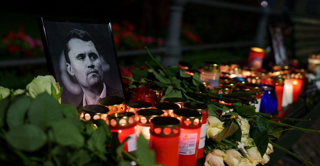 A photo of Charlie Kirk is surrounded by gifts, flowers and candles at a memorial.